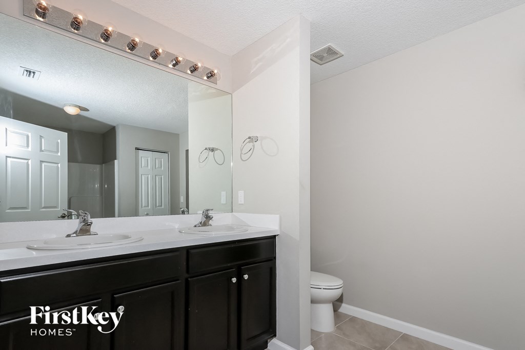 a bathroom with two sinks and a toilet and a mirror