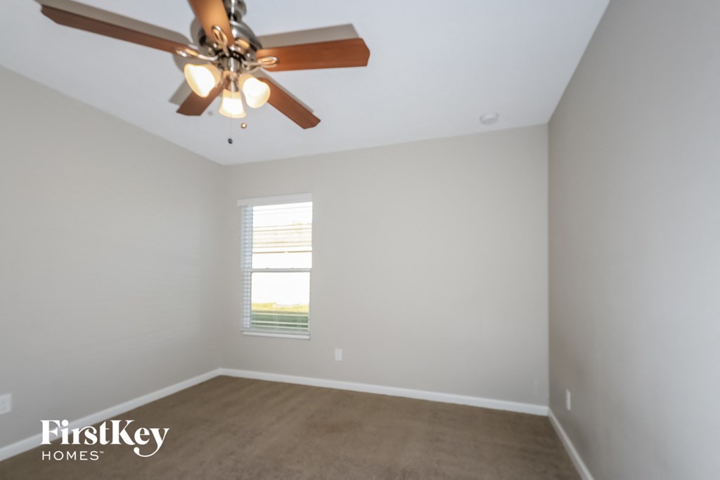 a empty room with a ceiling fan and a window