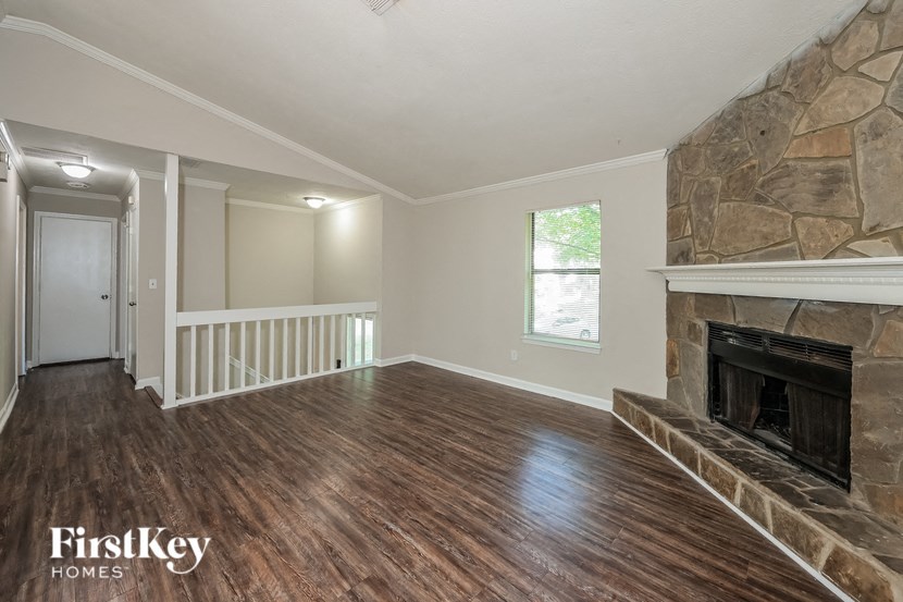 a living room with a stone fireplace and wooden floors