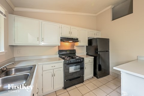 a kitchen with white cabinets and black appliances