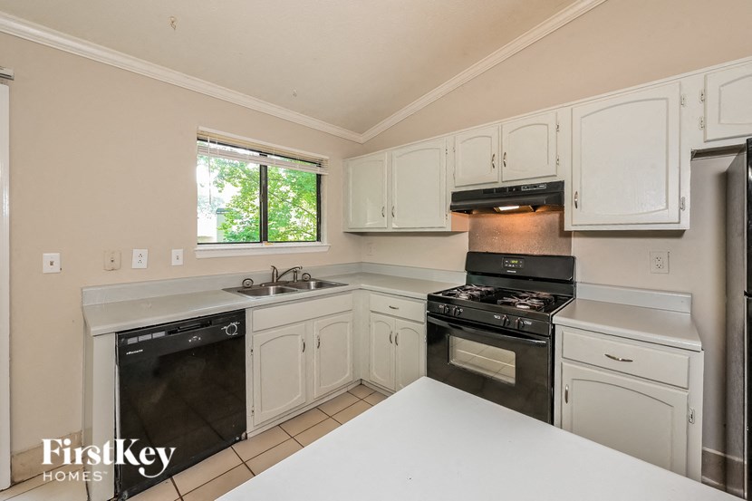 a white kitchen with black appliances and white counters