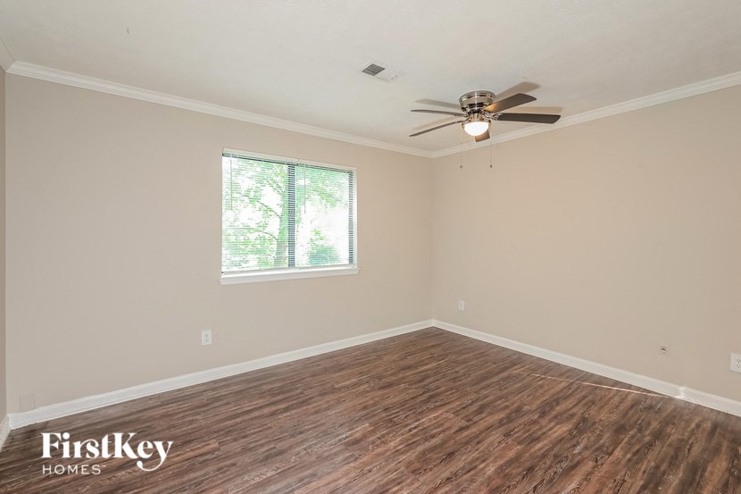 an empty living room with a ceiling fan and a window
