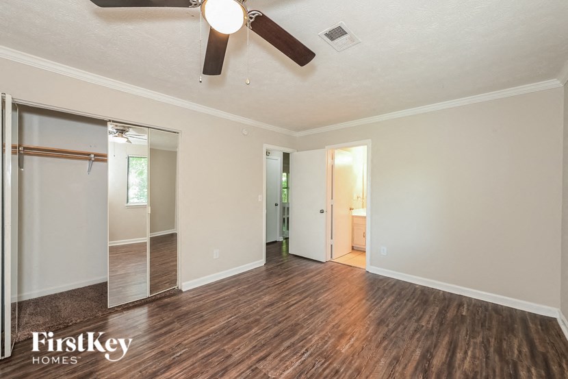 an empty living room with a ceiling fan and a closet