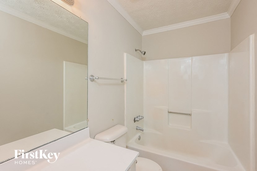 a white bathroom with a toilet and a shower