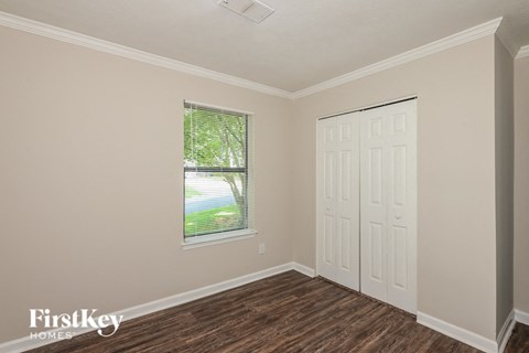 the bedroom of a home with a white door and a window