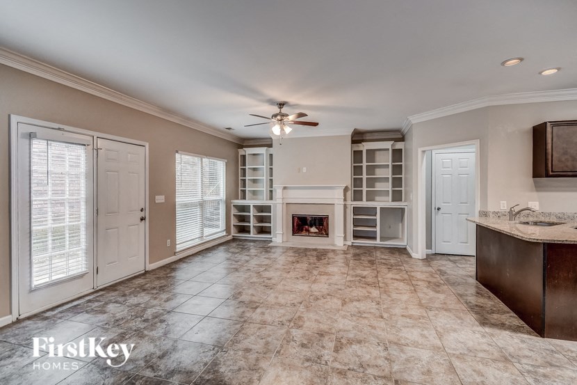 an empty living room with a fireplace and a kitchen