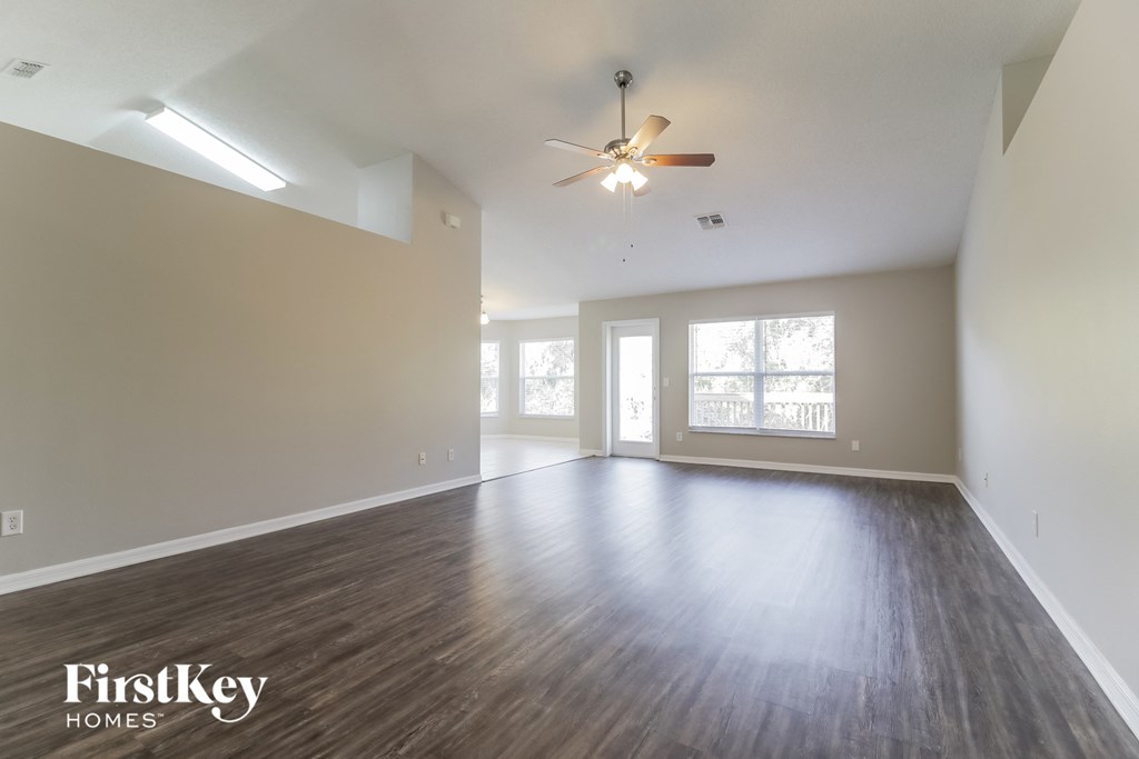 A spacious room with wooden floors and a ceiling fan.