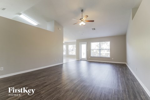 A spacious room with wooden floors and a ceiling fan.