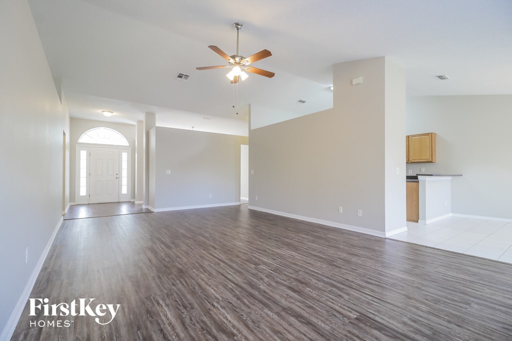 A spacious room with a ceiling fan and wooden flooring.