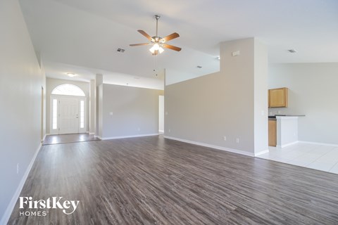 A spacious room with a ceiling fan and wooden flooring.