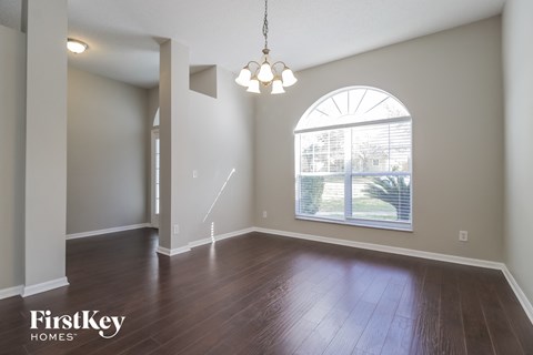 A room with wooden floors and a large arched window.