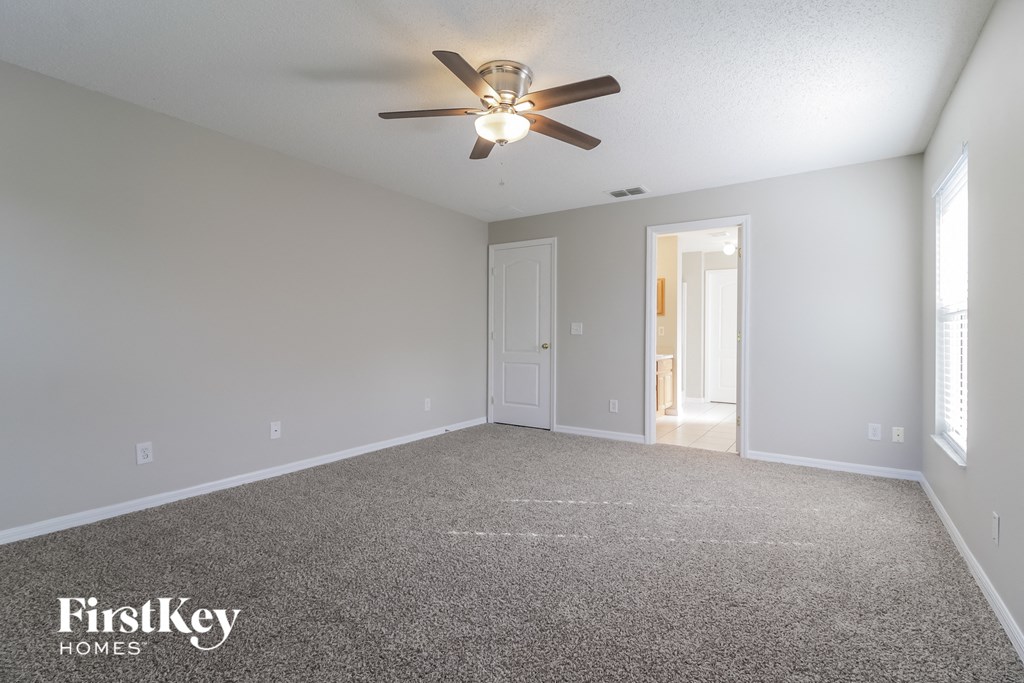 A spacious room with a ceiling fan and a carpeted floor.