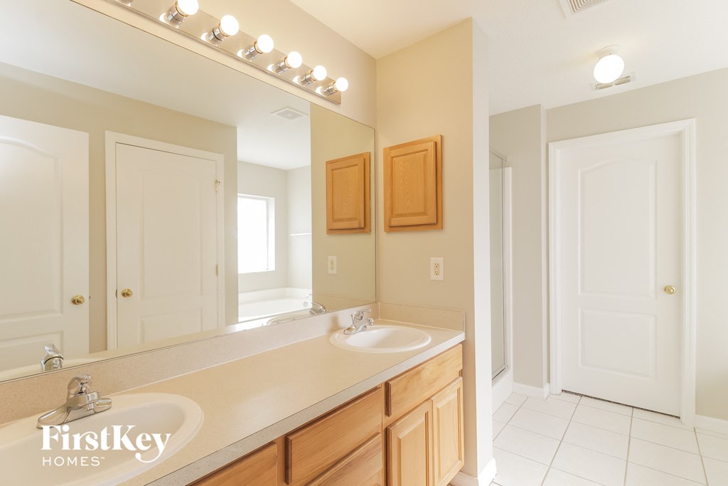 A bathroom with a sink, mirror, and lighting fixture.