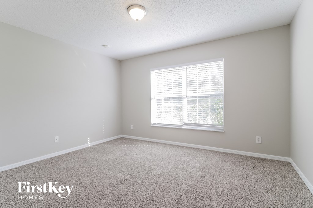 A room with a carpeted floor and a window with blinds.
