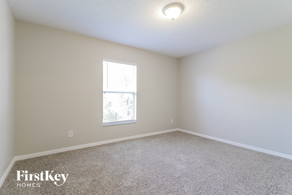 A room with a carpet floor and a window letting in light.