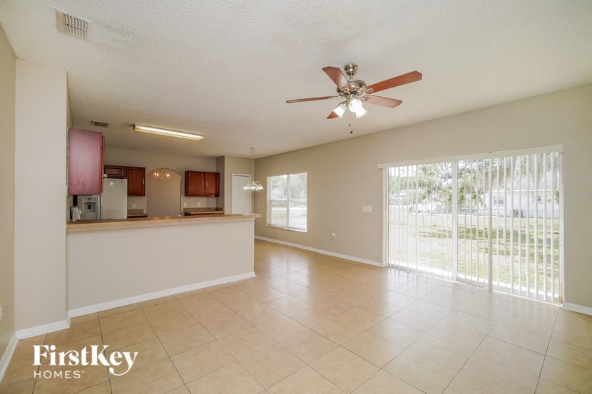 A spacious living room with a ceiling fan and sliding glass doors.