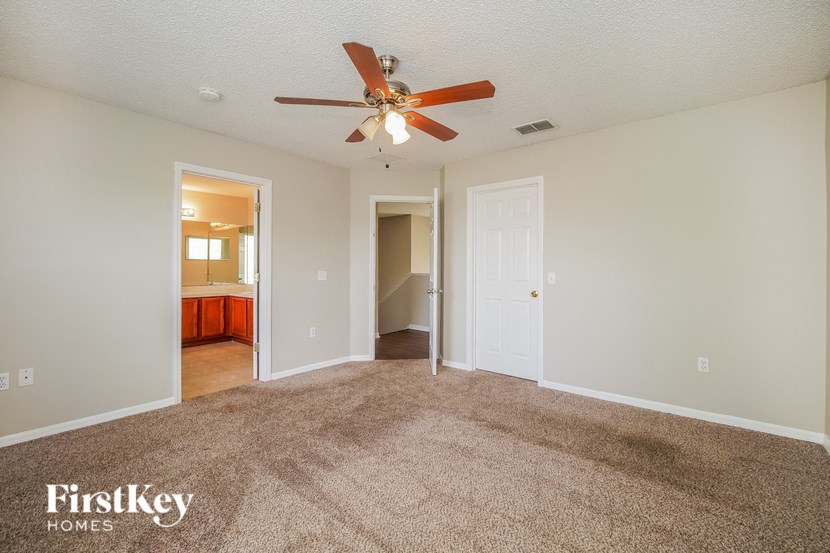 A spacious room with a carpeted floor and a ceiling fan.