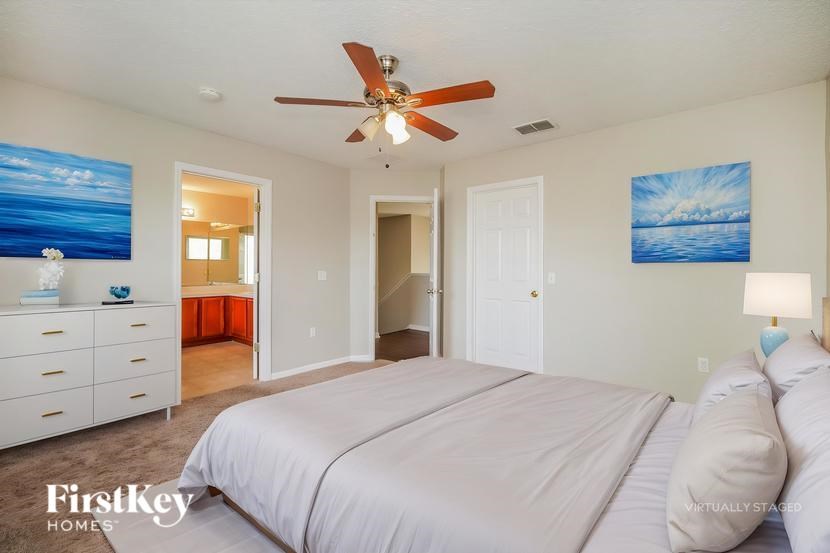 A bedroom with a large bed and a ceiling fan.
