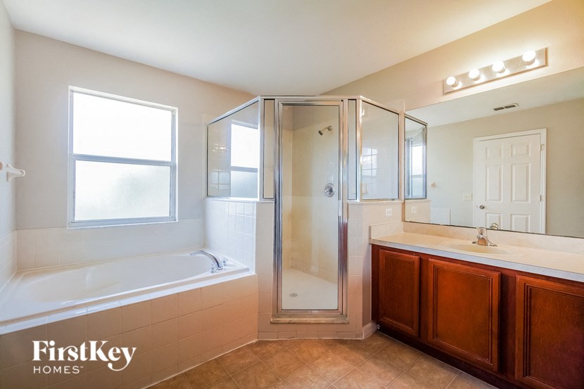 A bathroom with a tub, sink, mirror, and shower.