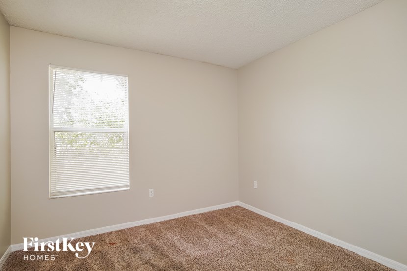 A room with a carpeted floor and a window with blinds.