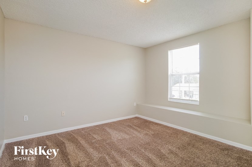 A room with a carpeted floor and a window letting in light.