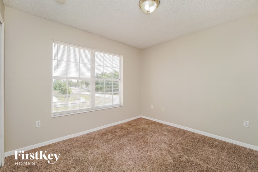 A room with a carpeted floor and a window with blinds.
