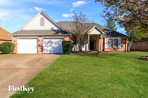 A house with a garage and a tree in front.