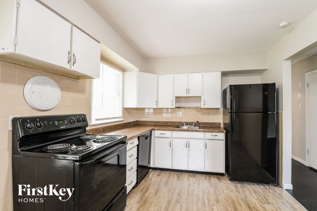 an empty kitchen with black appliances and white cabinets