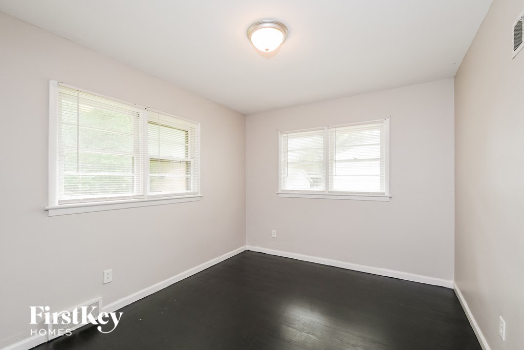 a bedroom with a black floor and two windows