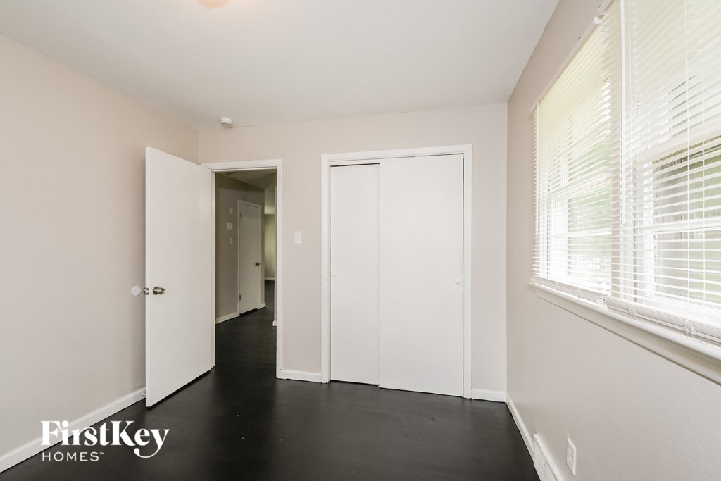 a bedroom with white walls and a black floor and a white closet