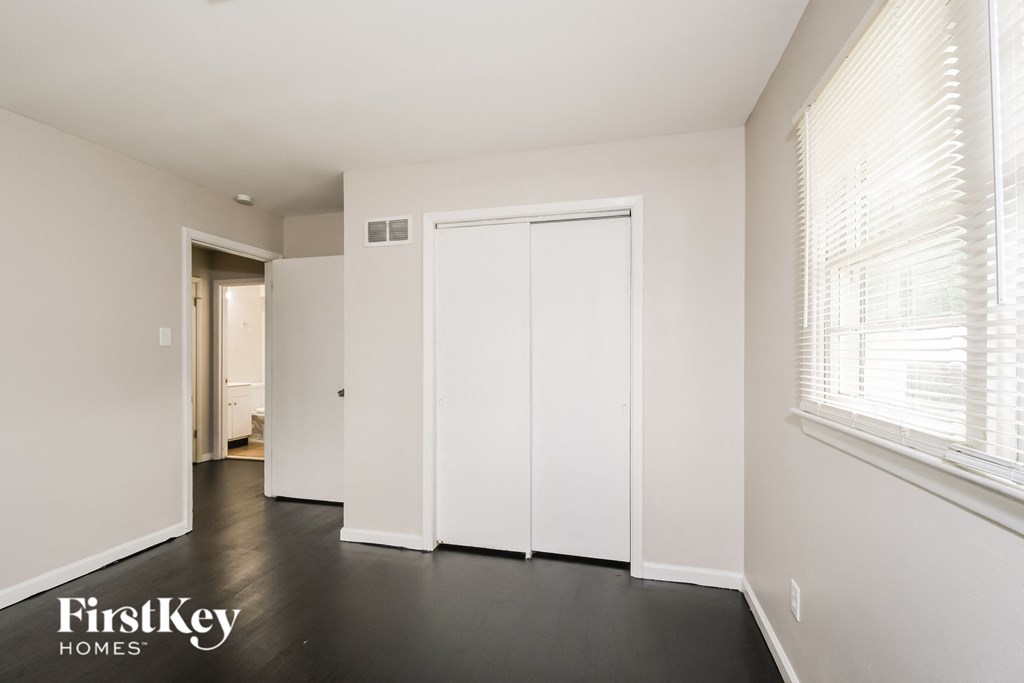 a bedroom with white walls and white closets and a large window