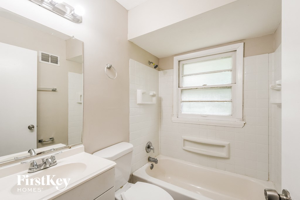 a white bathroom with a tub and a sink and a mirror