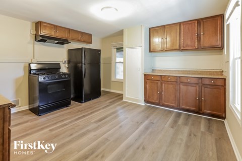 A kitchen with wooden cabinets and a black fridge.