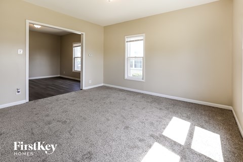 A spacious room with a carpeted floor and a window letting in natural light.