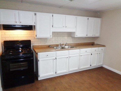 a kitchen with white cabinets and a sink and a stove