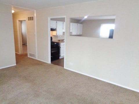 an empty living room with a kitchen in it