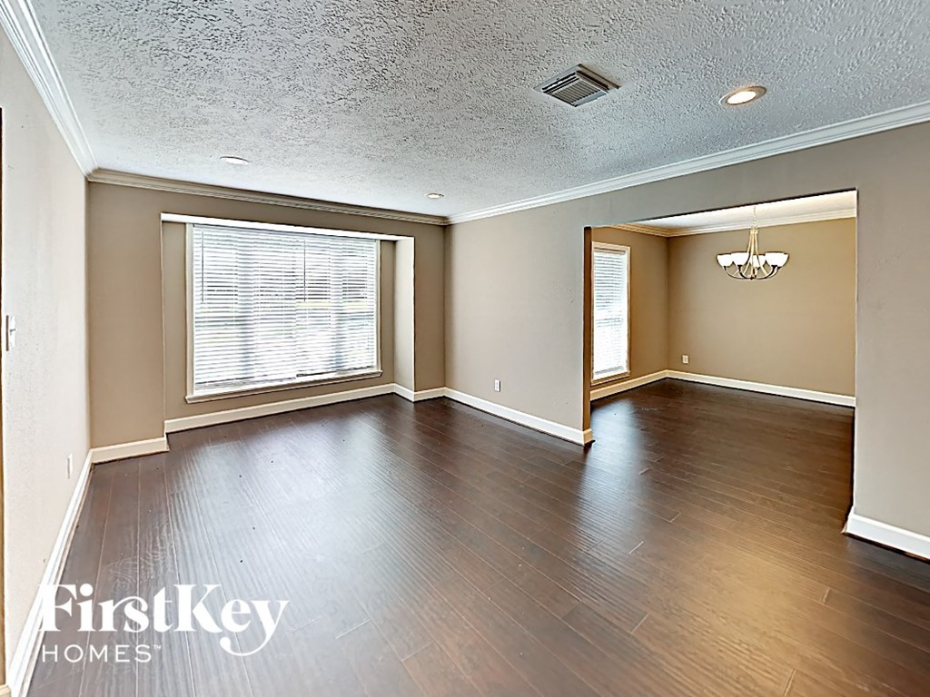 an empty living room with wood floors and a large window