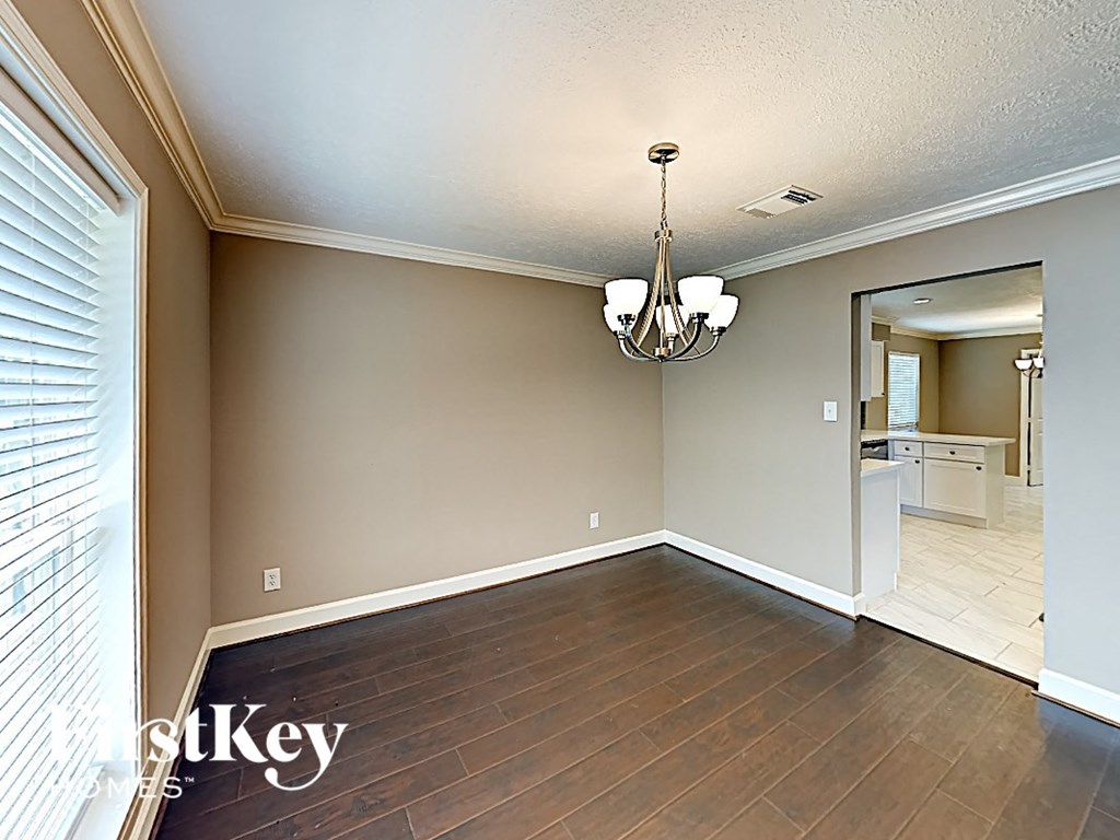 an empty dining room with wood flooring and a chandelier