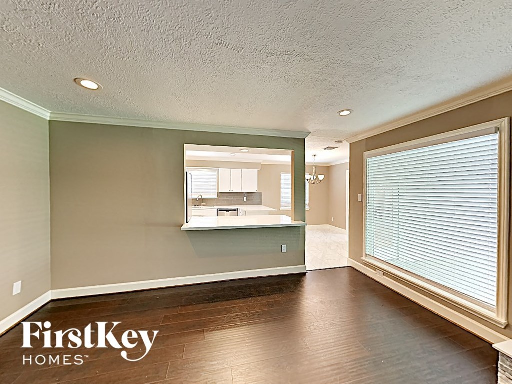 an empty living room with a large window and a kitchen
