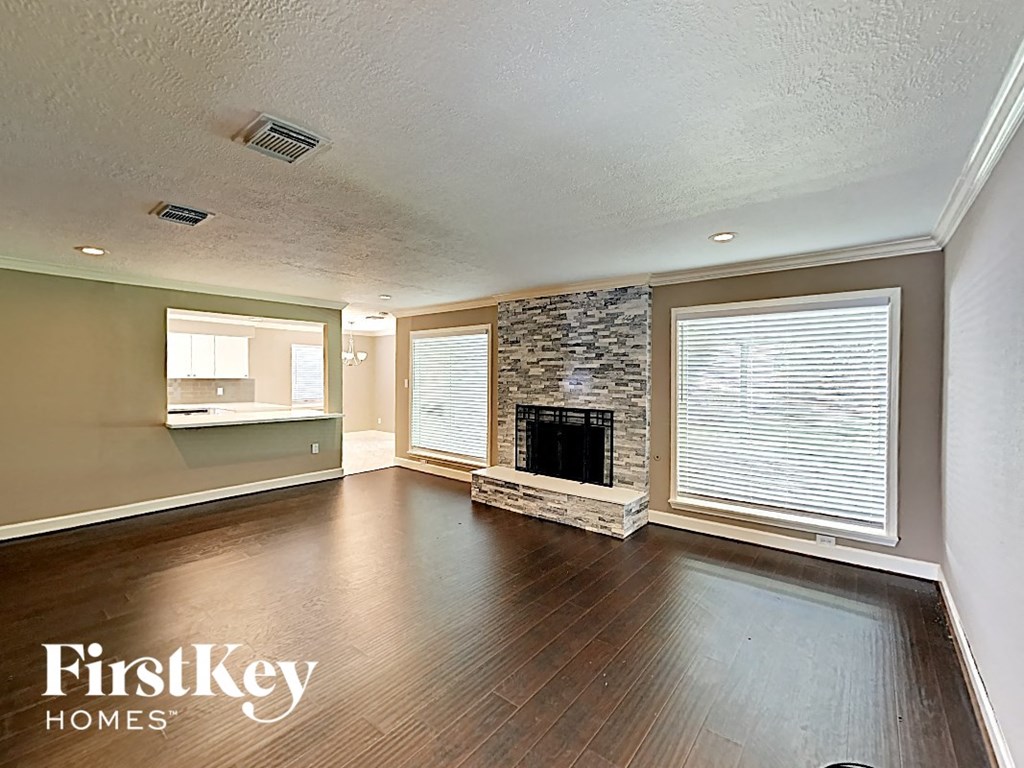 an empty living room with a fireplace and wood floors