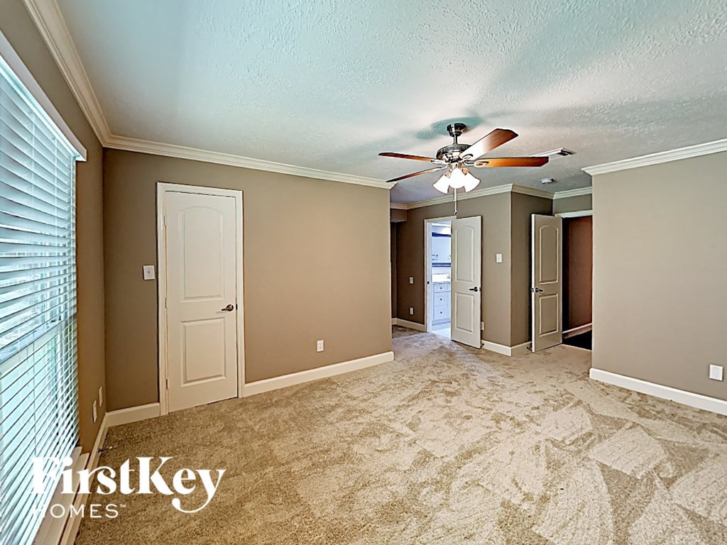 an empty living room with a ceiling fan and a closet