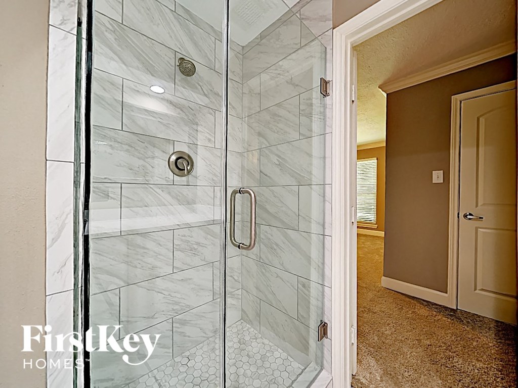 the master bathroom has a large walk in shower with marble tiles