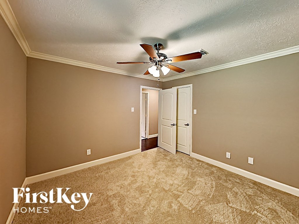 a bedroom with a ceiling fan and a door to a closet