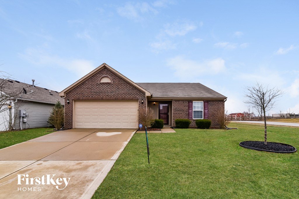 a brick house with a lawn and a driveway