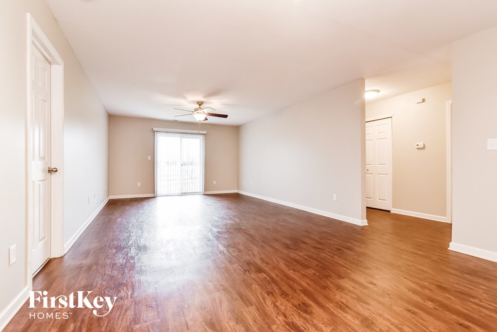 an empty living room with wood flooring and a ceiling fan