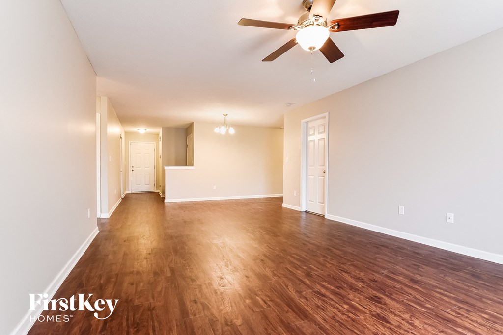 the living room and dining room of an empty house with a ceiling fan