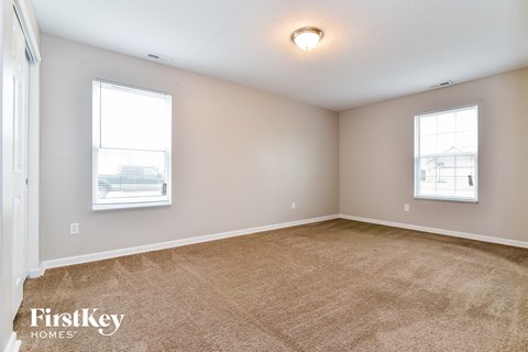 the living room of a house with carpet and two windows