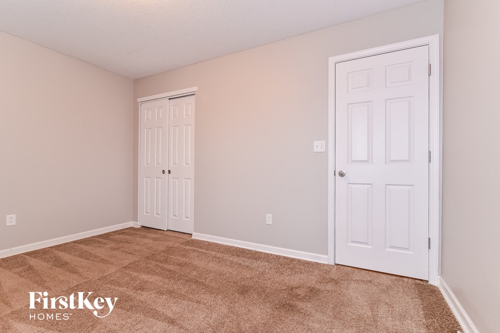 a bedroom with two doors and a carpeted floor