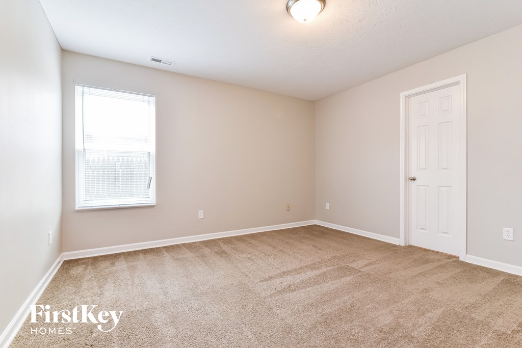 a spacious bedroom with carpeted flooring and a white door