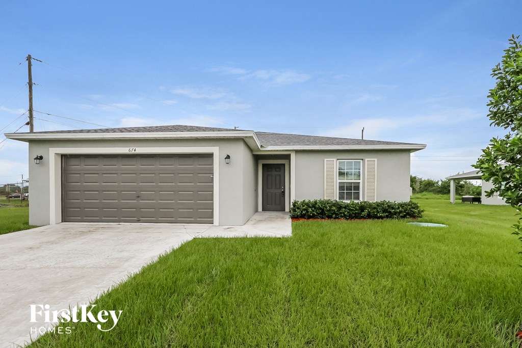 A house with a garage door and a lawn in front.